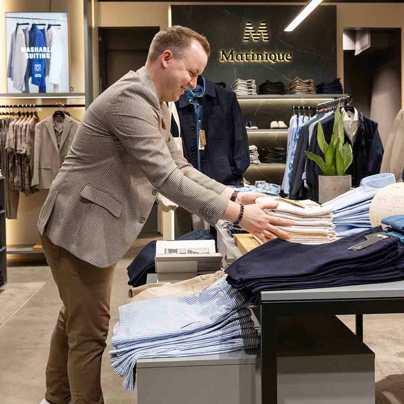 Medarbejder fra Matinique på Frederiksberg lægger tøj på hylder.